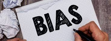 The word BIAS written in large black letters by a hand holding a pen on notebook paper